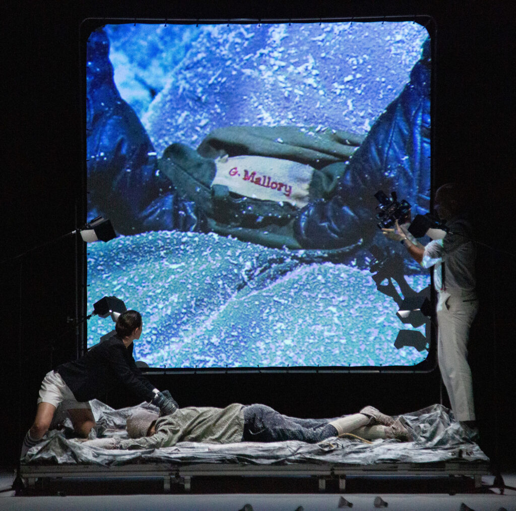 Les comédiens de The Mountain filmant des images sur scène, qui sont projetées sur un écran derrière eux, au Paris Globe Festival.