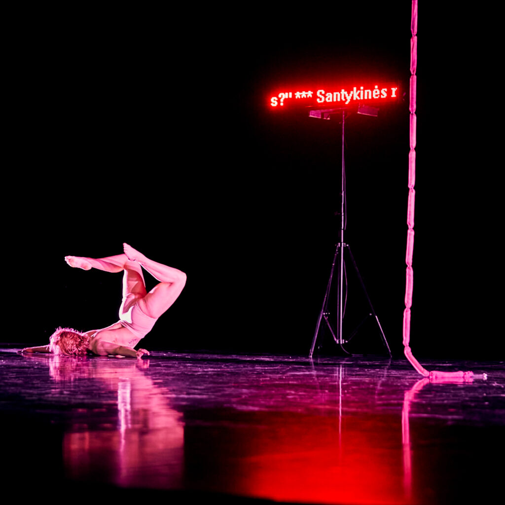 Une artiste de la compagnie lituanienne de cirque Taigi Cirkas se contorsionnant au sol à côté d'une corde en saucisses, dans le spectacle Saucisson, lors du festival révélations circusnext au Théâtre de la cité internationale.