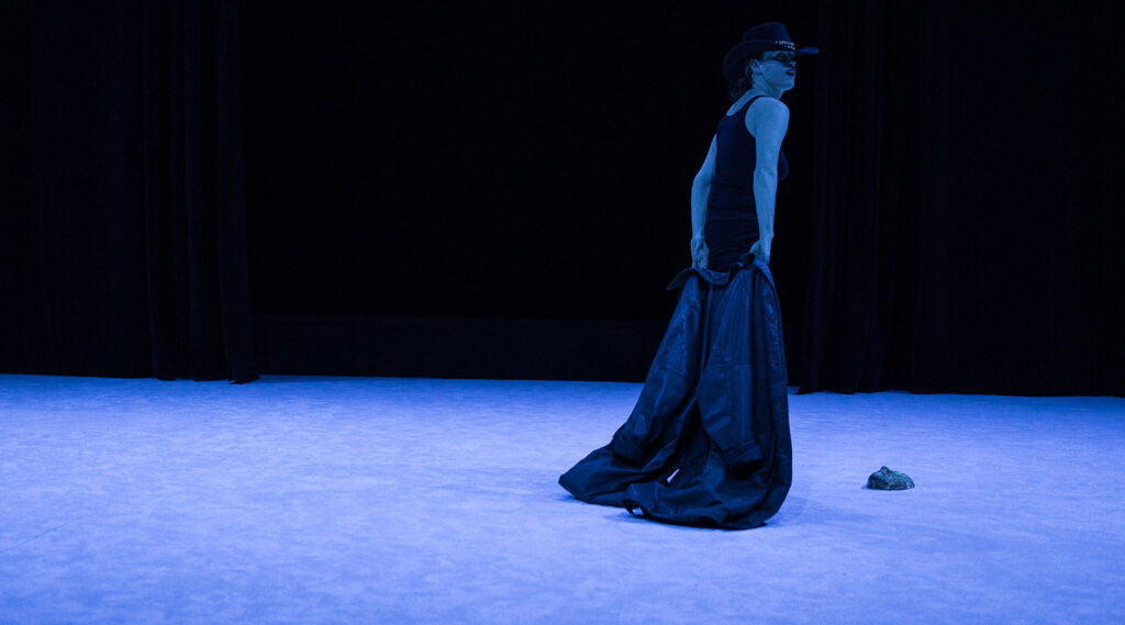 Julia Perazzini avec un chapeau de cow-boy, dans une lumière spectrale, dans le spectacle Dans ton intérieur, au Théâtre Public de Montreuil