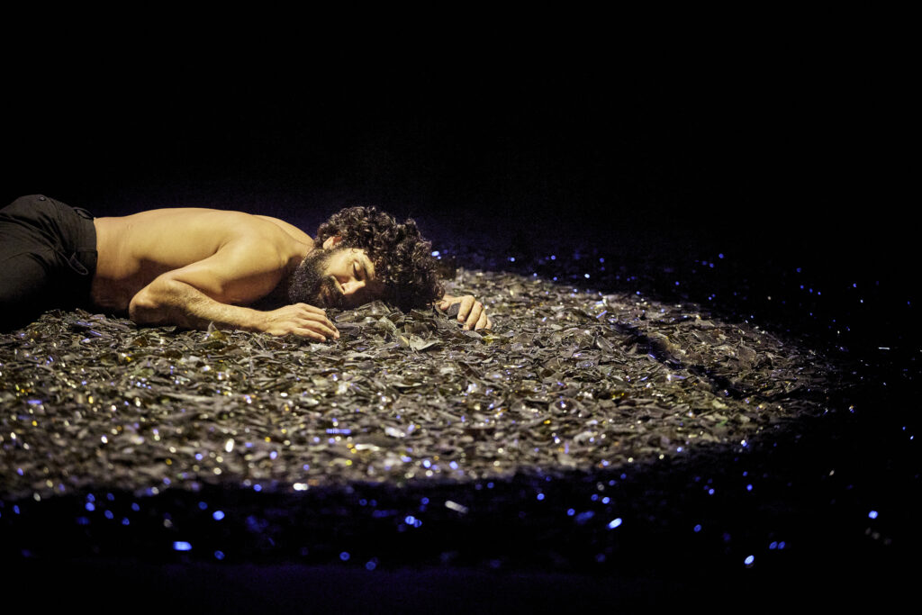 Marcelo Nunes allongé sur un parterre de morceaux de verre.